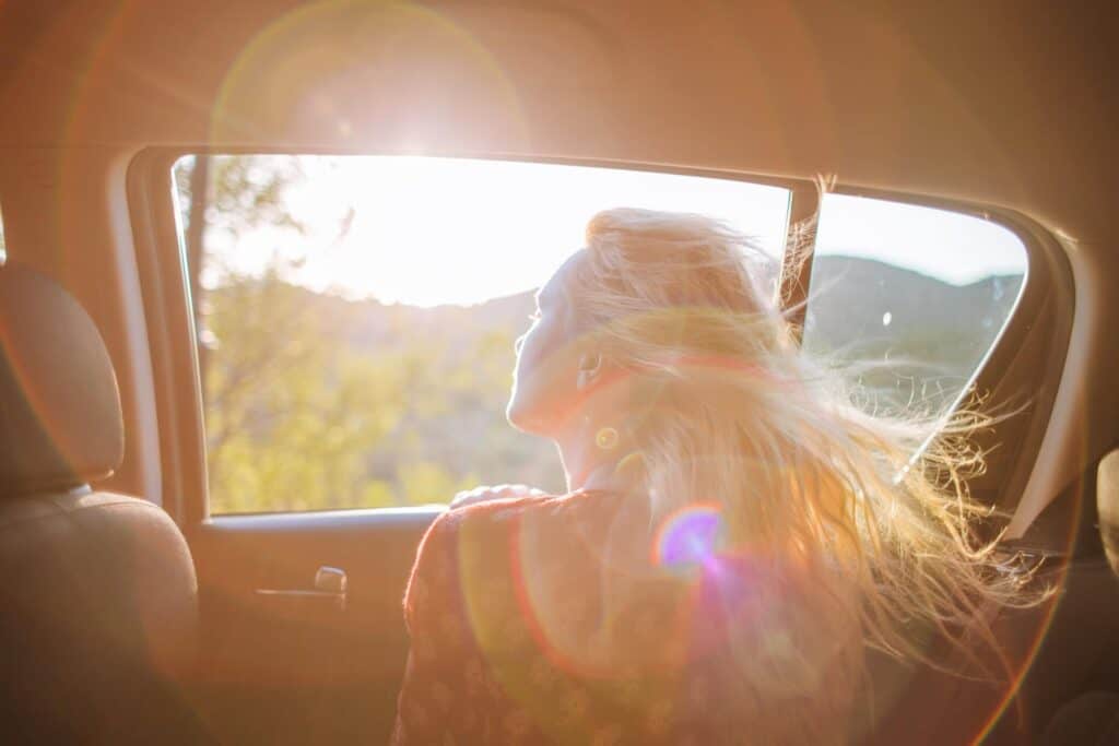 Girl looking out of car window on road trip